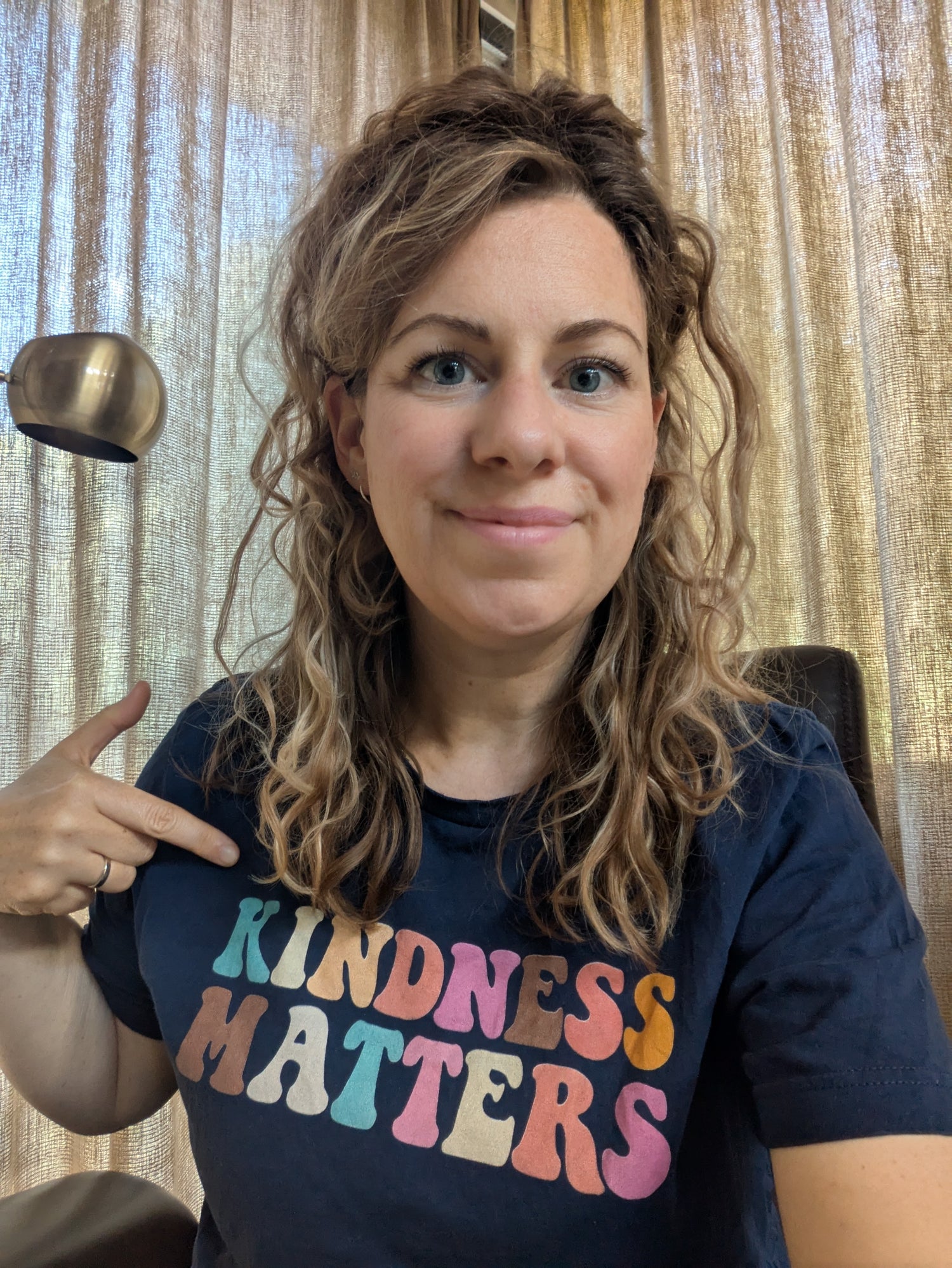 Portret van Michèlle. Ze wijst naar haar t-shirt, daar staat in het Engels op: kindness matters.