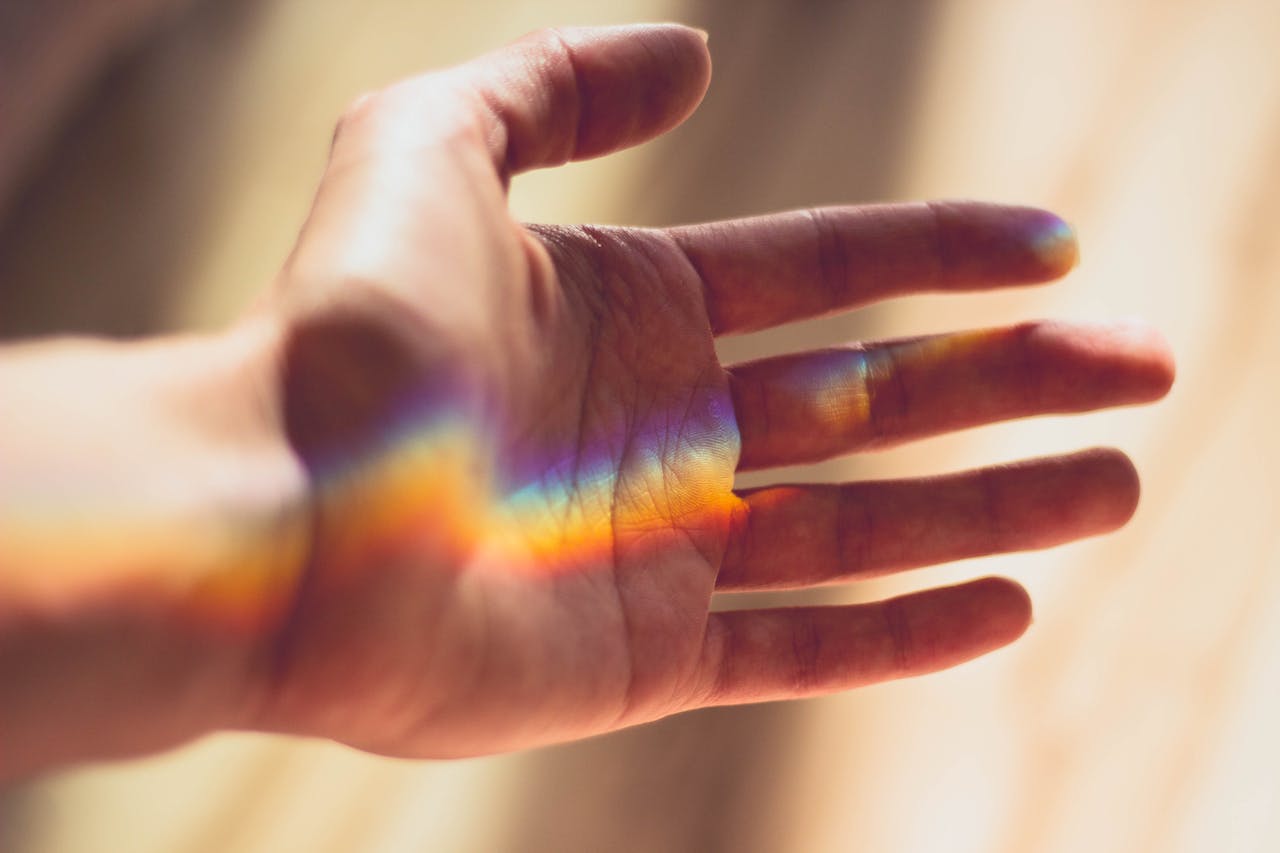 handpalm waarop een streep licht in regenboogkleuren valt
